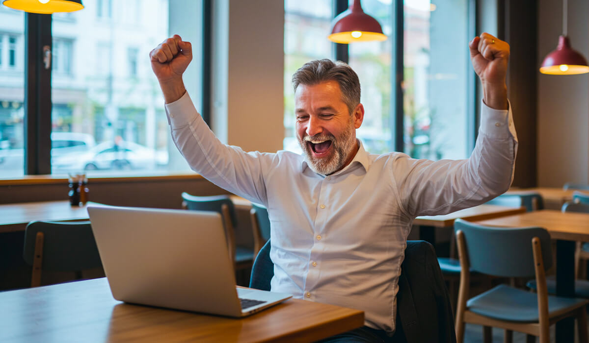 A customer celebrating while looking at his laptop in a restaurant
