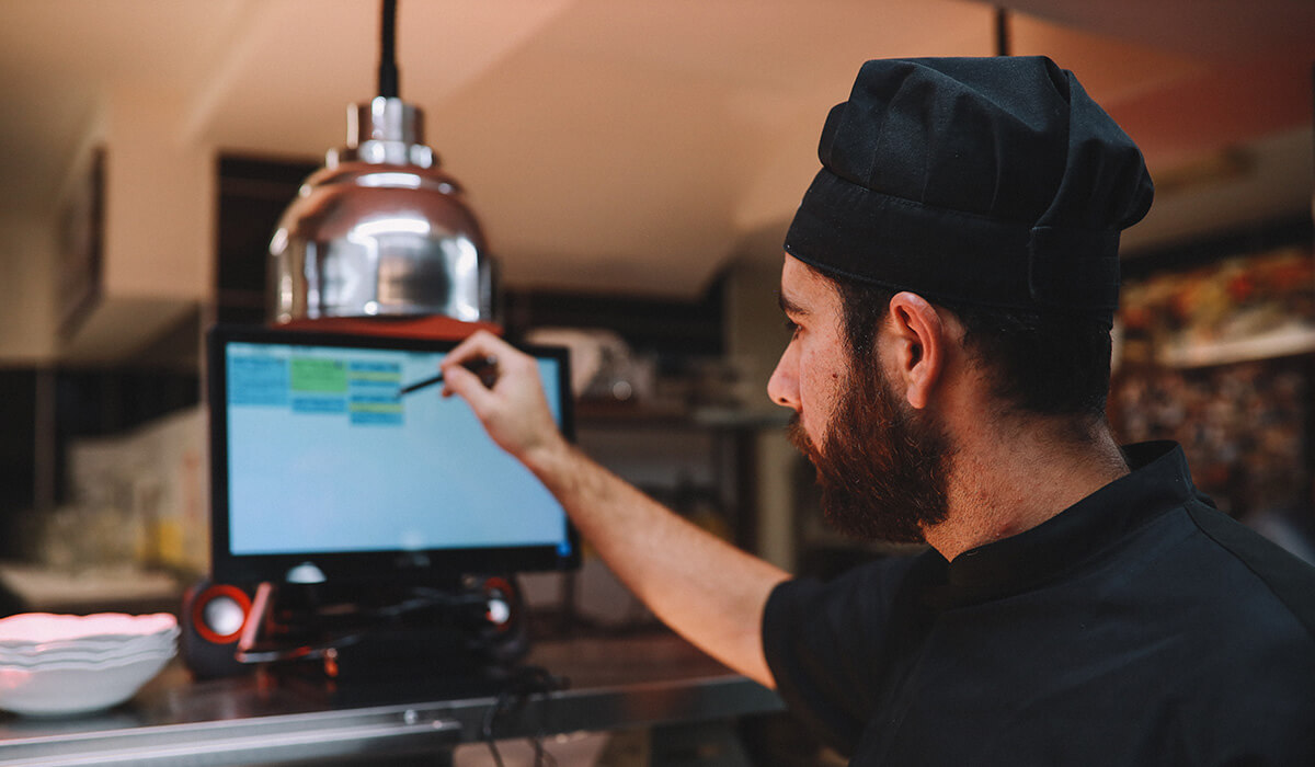 A chef using a kitchen display screen that's integrated with PowerEPOS