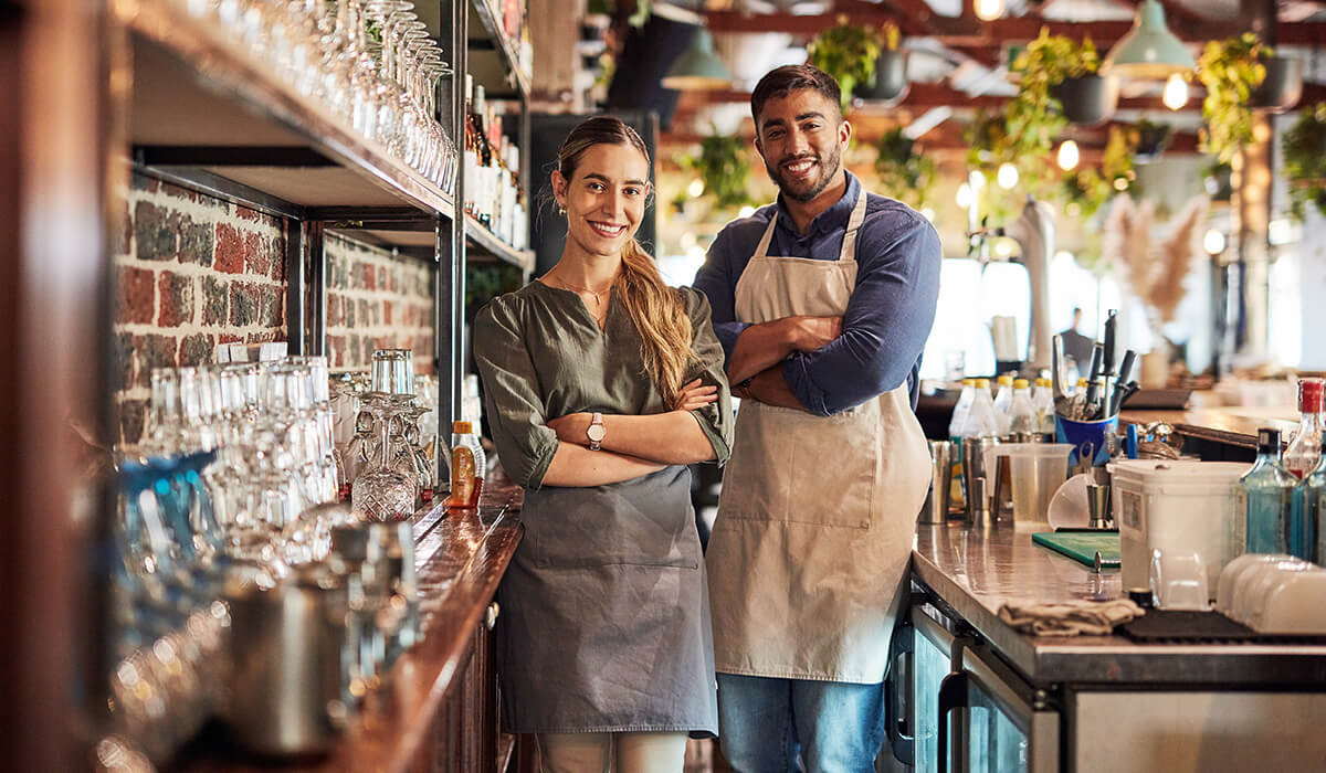 Happy business owners standing in their bar. 