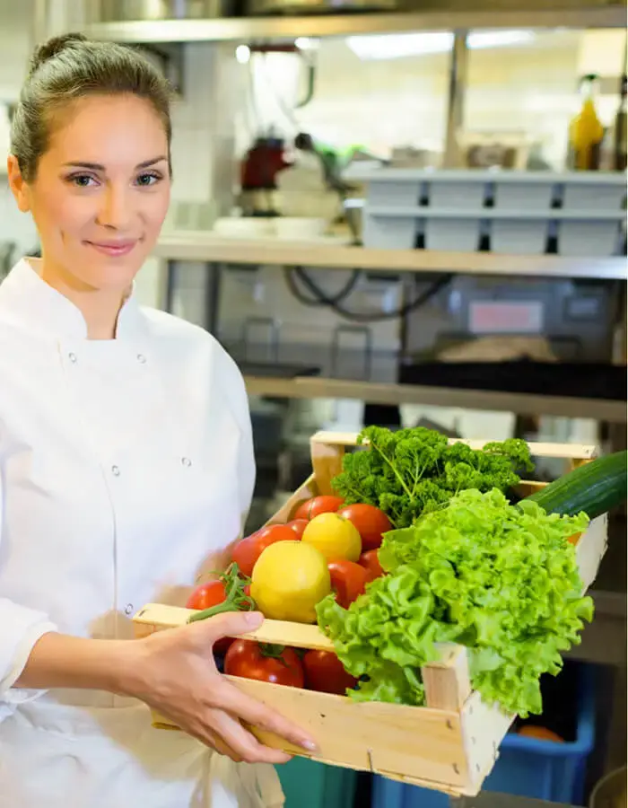 A chef holding a crate of produce