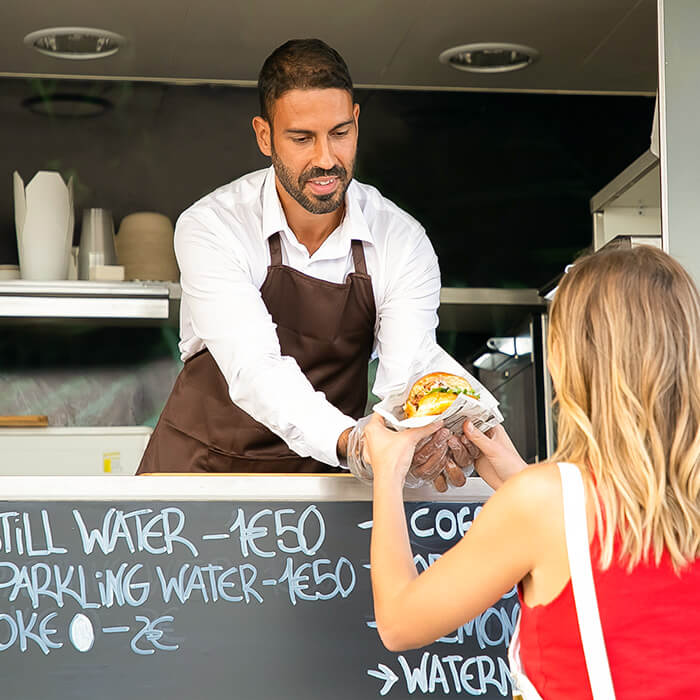 A man handing a woman a burger from a food truck