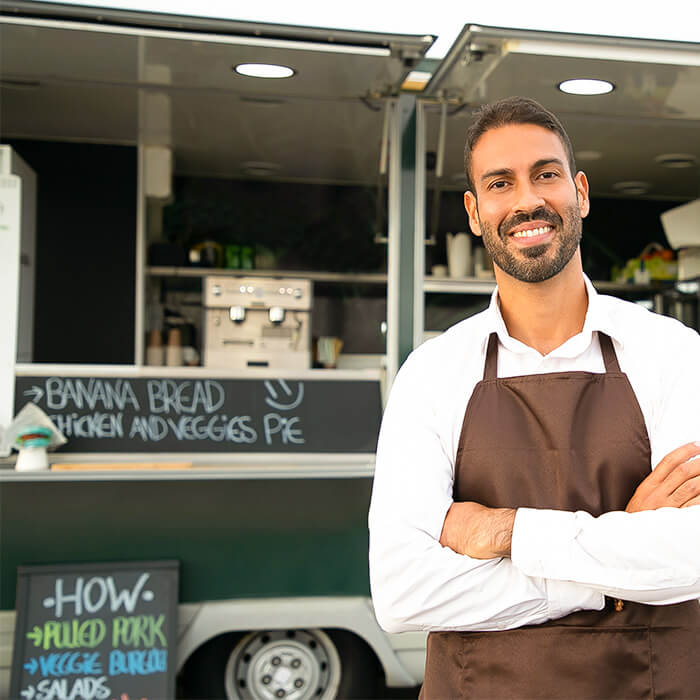 Happy staff member standing in front of a food truck