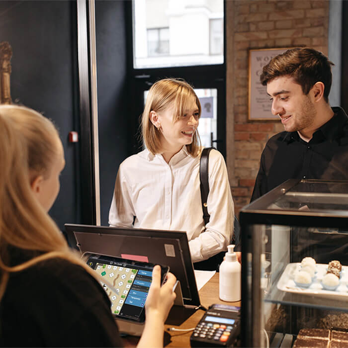 A woman taking a payment from a couple at a hotel cafe