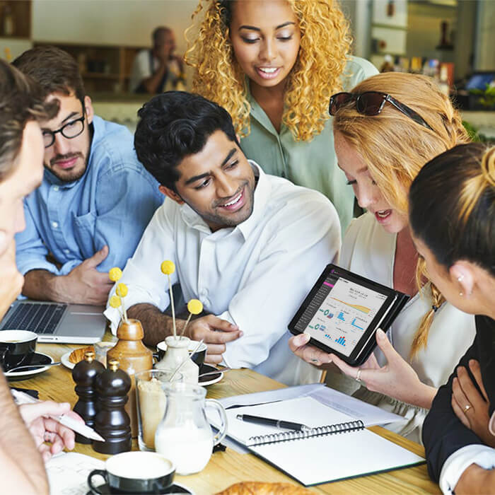 PowerEPOS on a tablet being held by a woman with her colleagues looking on.