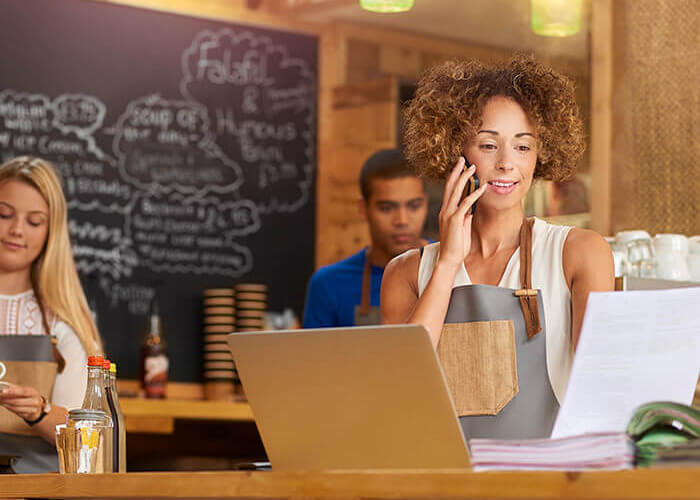 A cafe business owner behind the counter on her phone.