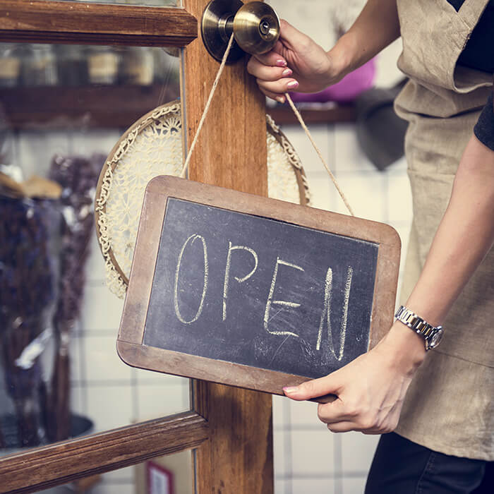 A woman setting a sign as open on a cafe door