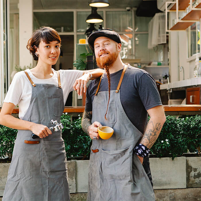 Business owners standing in front of their cafe smiling