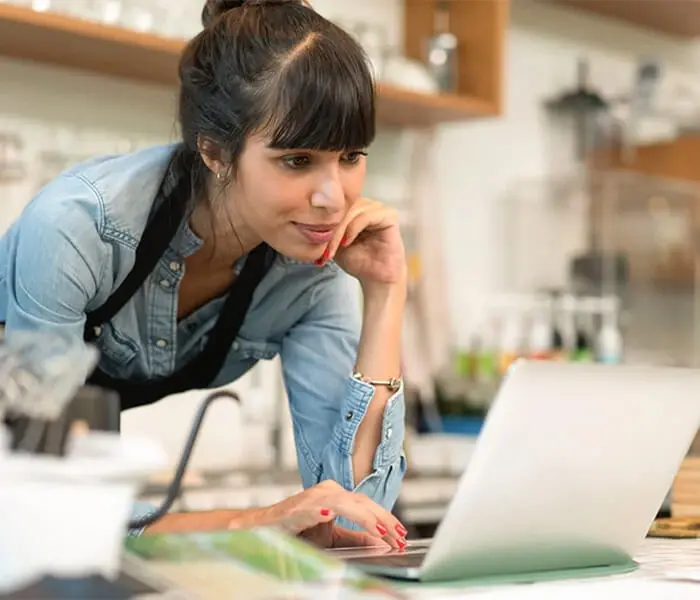 A hospitality business operator looking at reports on her laptop