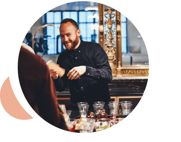 Bartender smiling while shaking a cocktail behind the bar