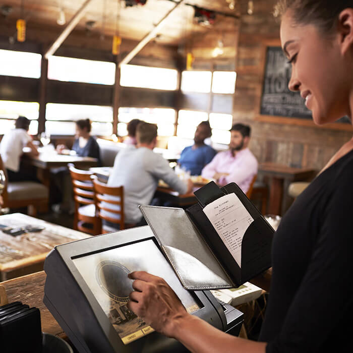 A woman entering an order into WaiterPOS with cusotmers in the background