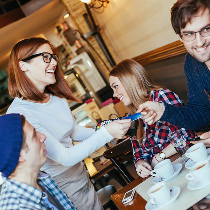 A woman taking a card payment from a customer in a cafe